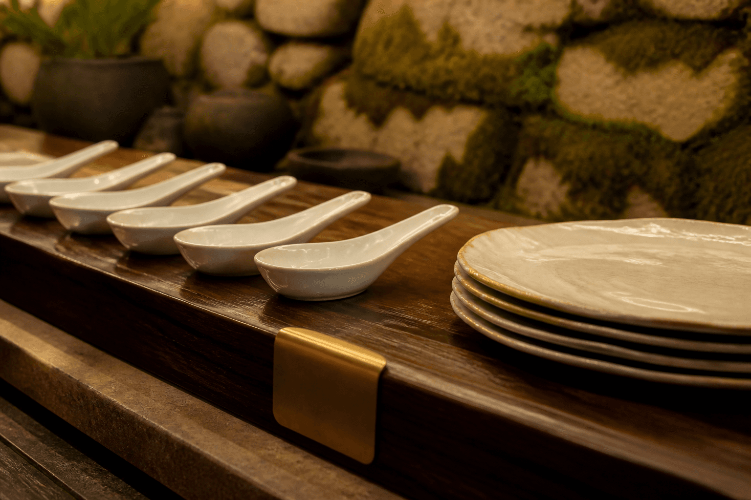 Unused tasting spoons and unused ivory plates in a quiet row on a koa pass, brass clip.