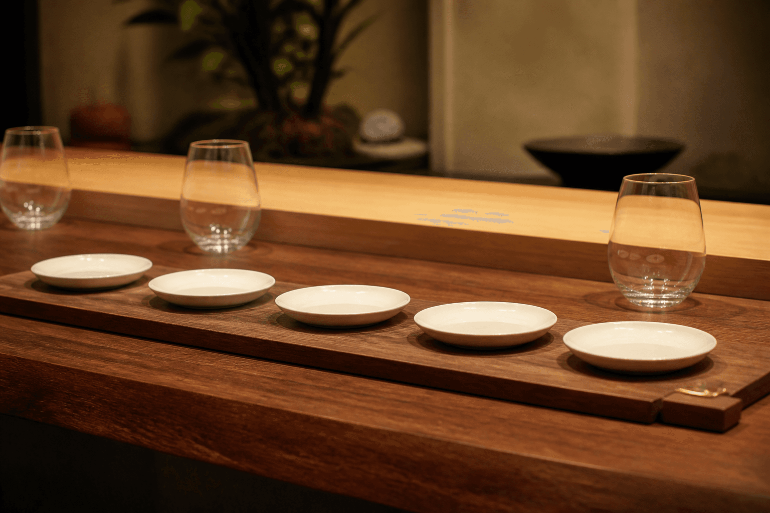 Unused small ivory tasting plates in a quiet row on a koa pass, brass clip, no writing.