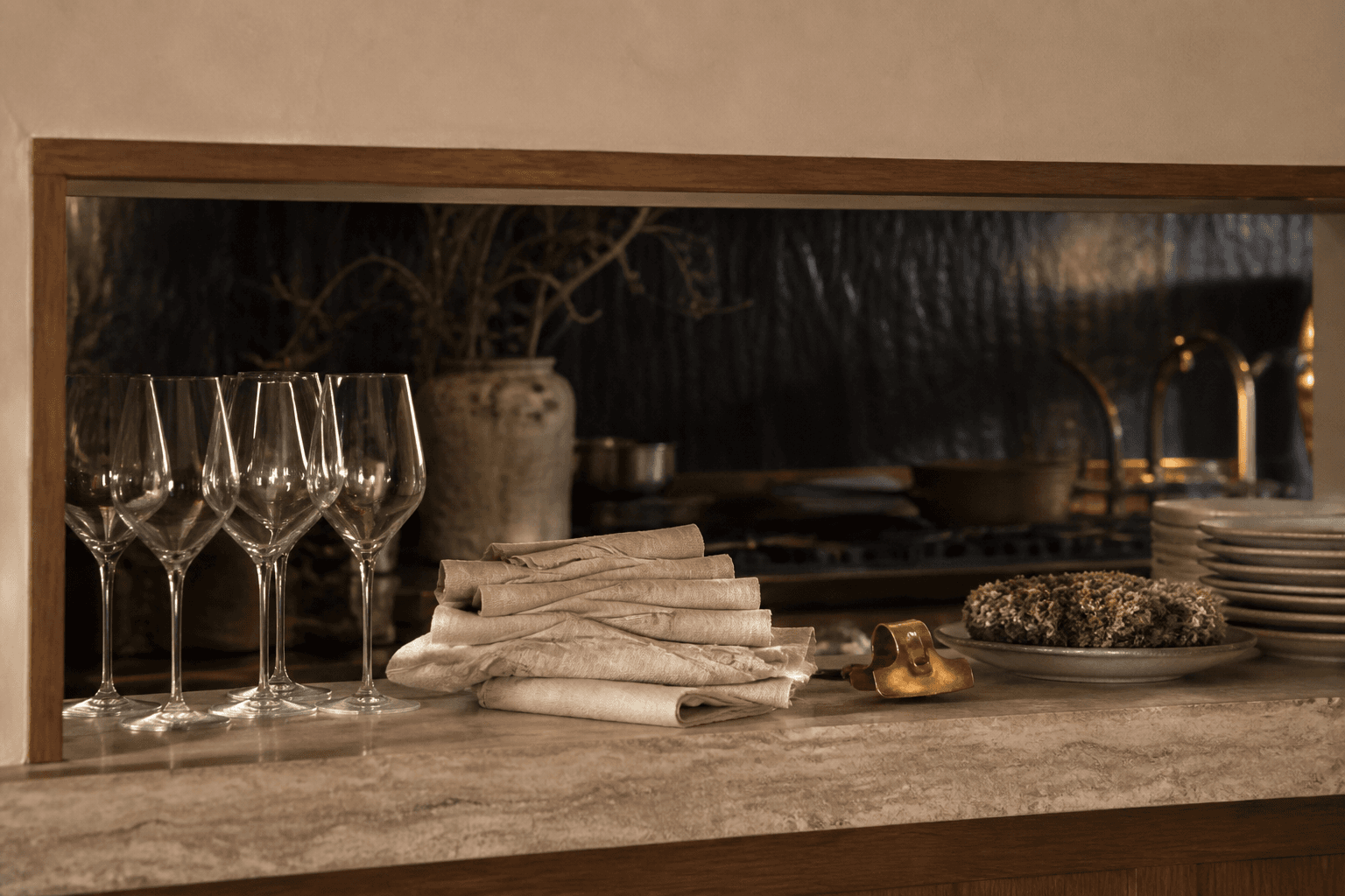 Unused empty glasses and sand linen on a kitchen pass, brass clip, no writing.